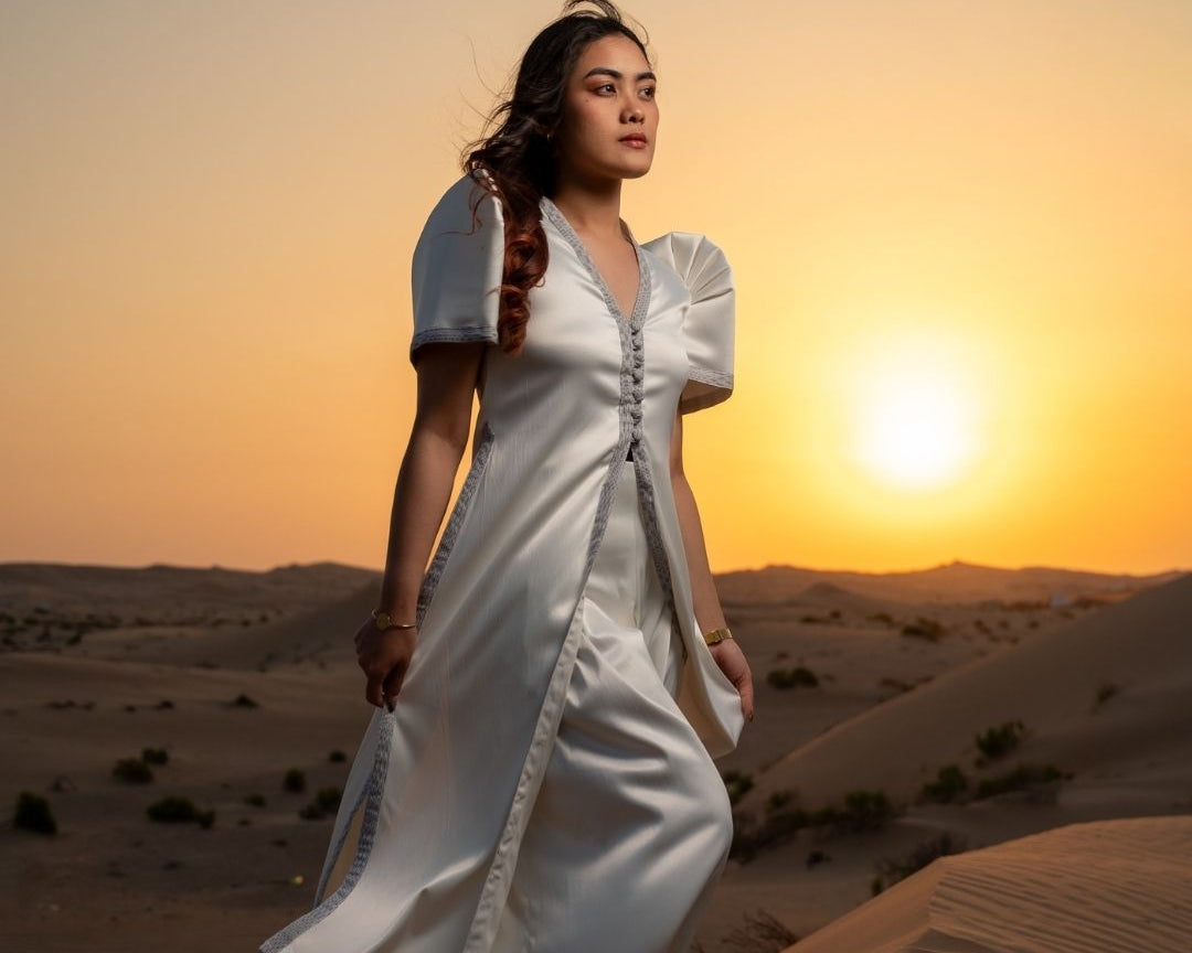 Woman in a white TERNO dress standing in a desert landscape with a sunset.