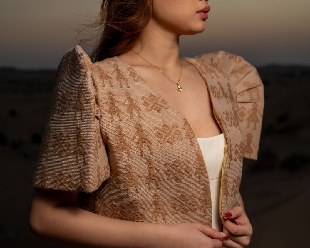 Woman wearing a patterned beige top against a desert backdrop